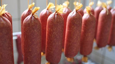 Wurstspezialitäten aus eigener Herstellung Frisch hergestellte Wurstspezialitäten zum Reifen aufgehängt