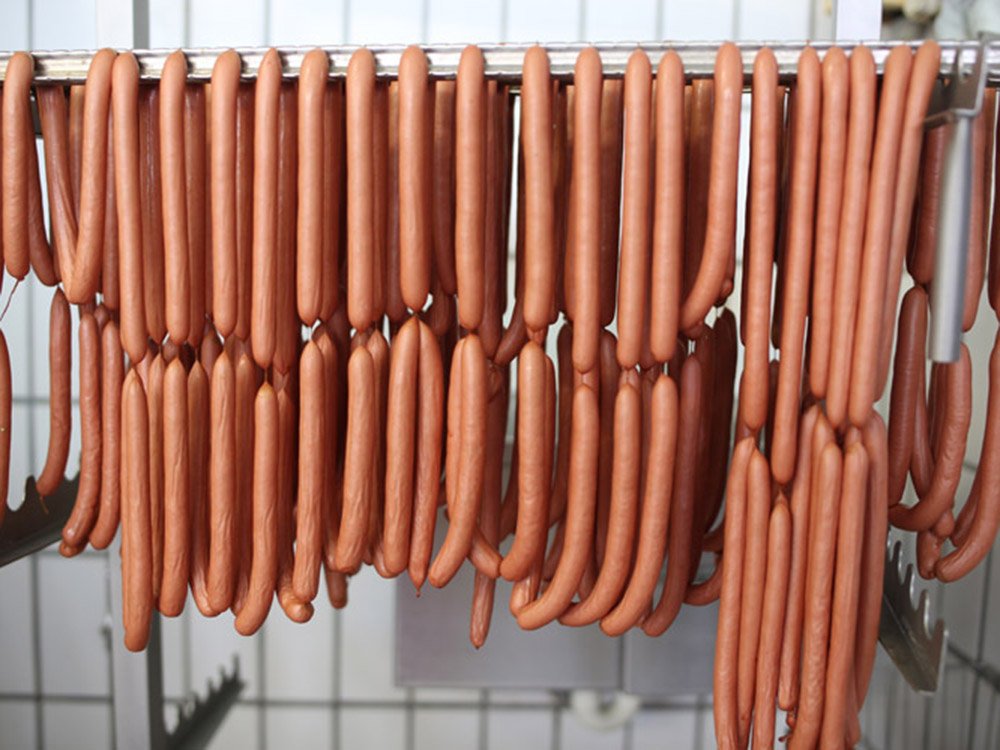 Würstchen aus eigener Herstellung Frisch hergestellte Würstchen hängen zur weiteren Verarbeitung in der Fleischerei